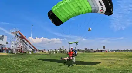 Hombre en tándem a punto de aterrizar bajo un cielo despejado
